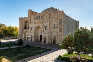 Zu sehen ist die Magok-i-Attari-Moschee in Buchara, eines der ältesten Bauwerke der Stadt. Ihre Fassade beeindruckt mit filigranen Ziegelmustern und kunstvollen Verzierungen, die die architektonische Entwicklung von vorislamischer Zeit bis zur islamischen Ära widerspiegeln. 