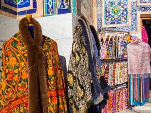  Zu sehen ist traditionelle usbekische Kleidung vor dem Registan-Ensemble in Samarkand, die mit leuchtenden Farben, aufwendigen Stickereien und kunstvollen Mustern die kulturelle Vielfalt und das reiche Erbe Usbekistans widerspiegelt. 