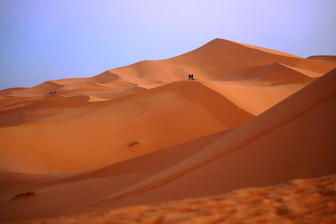 Eine sonnige Wüstenlandschaft mit Teilnehmern einer Marokko Rundreise