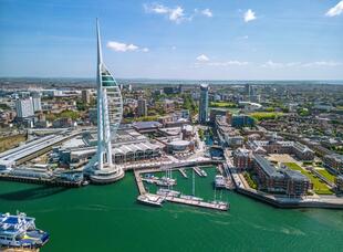 Draufsicht auf den Spinnaker Tower und den Hafen von Portsmouth. Der ikonische Turm in seiner markanten Segelform ragt über das lebhafte Hafenviertel hinaus.