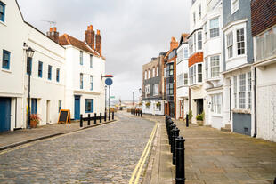 Leere Straße mit historischen Häusern in Old Portsmouth. Kopfsteinpflaster und charmante, alte Backsteinhäuser schaffen eine ruhige und authentische Atmosphäre.