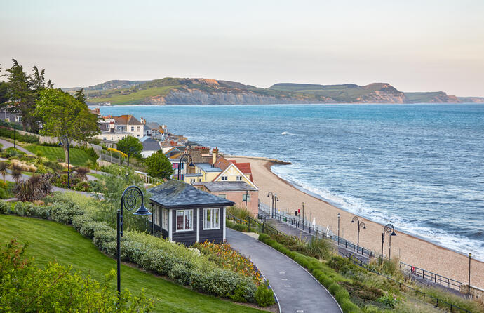 Die Seafront-Gärten von Lyme Regis, mit Blick auf die Jurassic Coast. Die gepflegten Gärten mit bunten Blumen und grünen Rasenflächen bieten einen wunderschönen Ausblick auf das Meer und die dramatischen Klippen der Jurassic Coast.